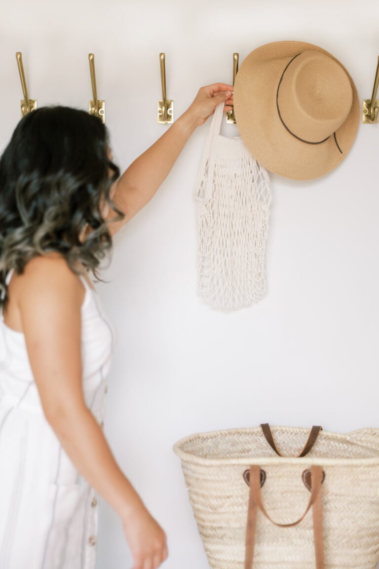 Young woman choosing a hat and bag, representing the beauty of building a routine that brings joy and balance to daily life.